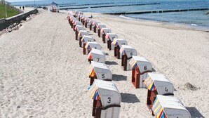 A beach with rows of numbered beach huts along the shoreline.