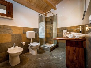 A bathroom with a bidet, toilet, shower, and wooden vanity with towels. - Villa in Sicily Near Guidaloca Bay (Castellammare del Golfo)