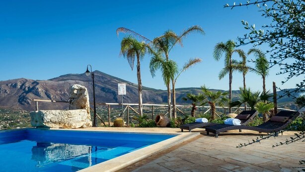 A pool area with lounge chairs and a view of a mountain. - Villa in Sicily Near Guidaloca Bay (Castellammare del Golfo)