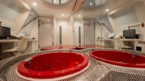 A modern bathroom with two red hot tubs, a large mirror, and a computer desk. - Aria Motel (Busan)