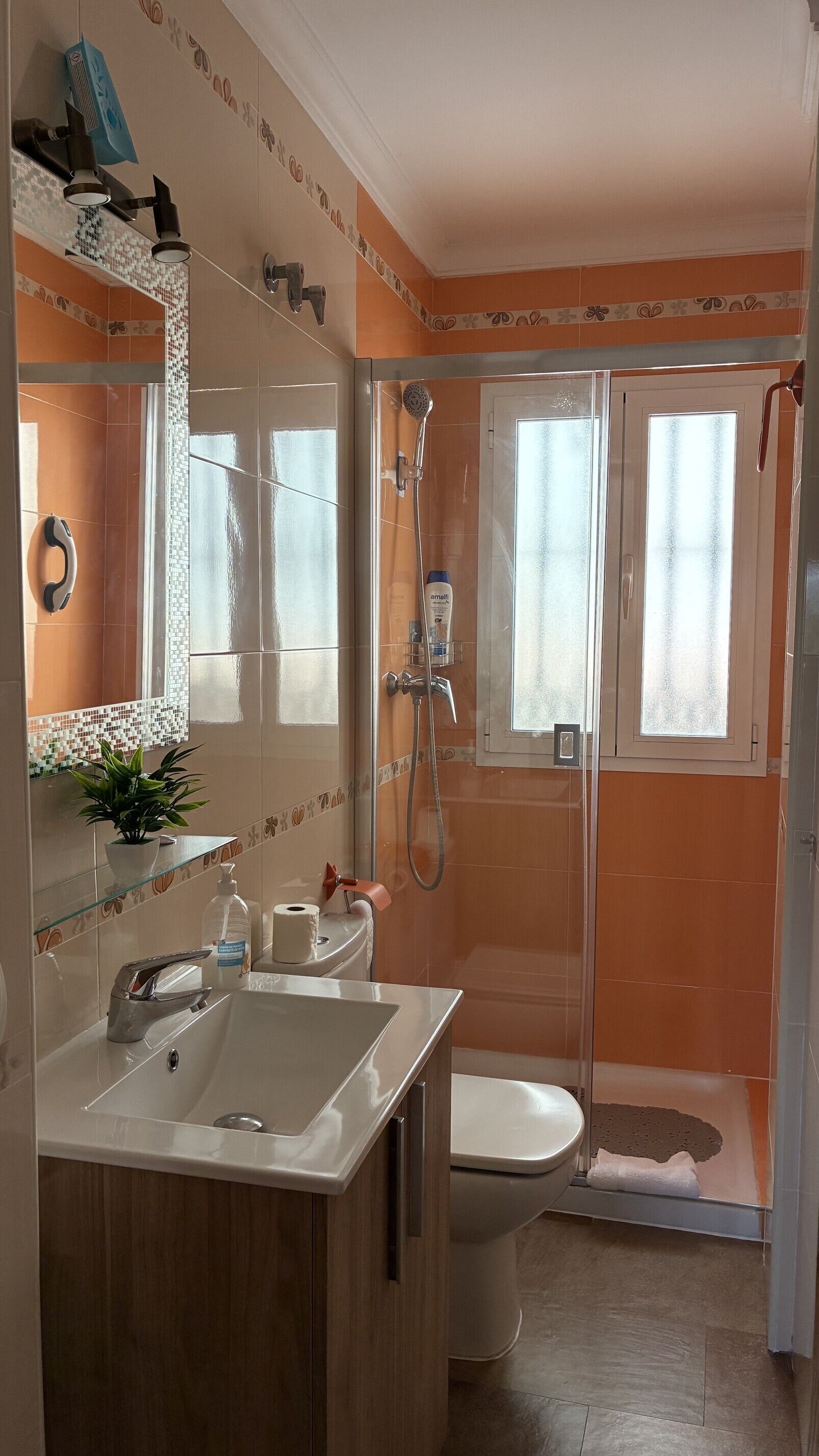 Un baño con lavamanos, inodoro y zona de ducha.