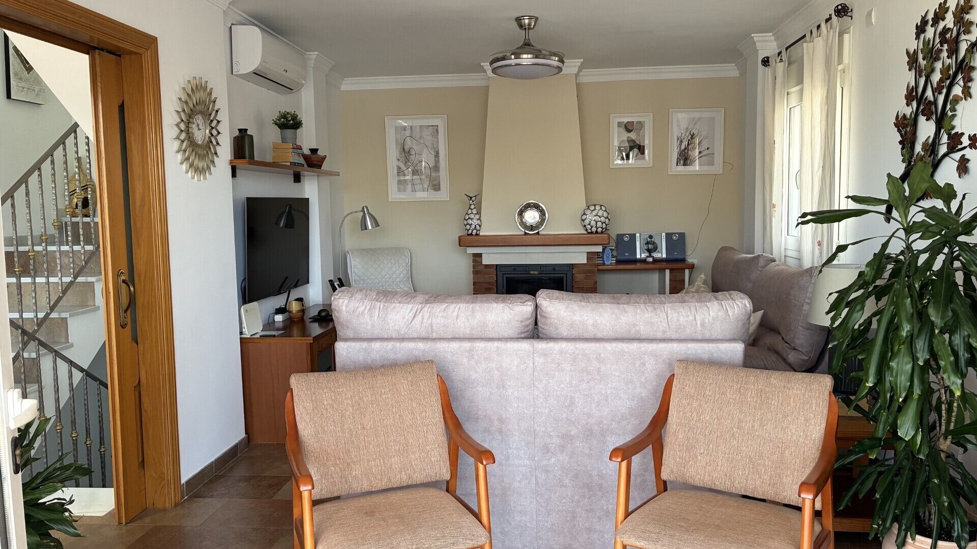 A living room with a sofa, two chairs, a fireplace, and a television.