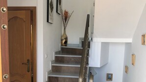 Una escalera con barandilla, una puerta de madera y una planta en maceta.