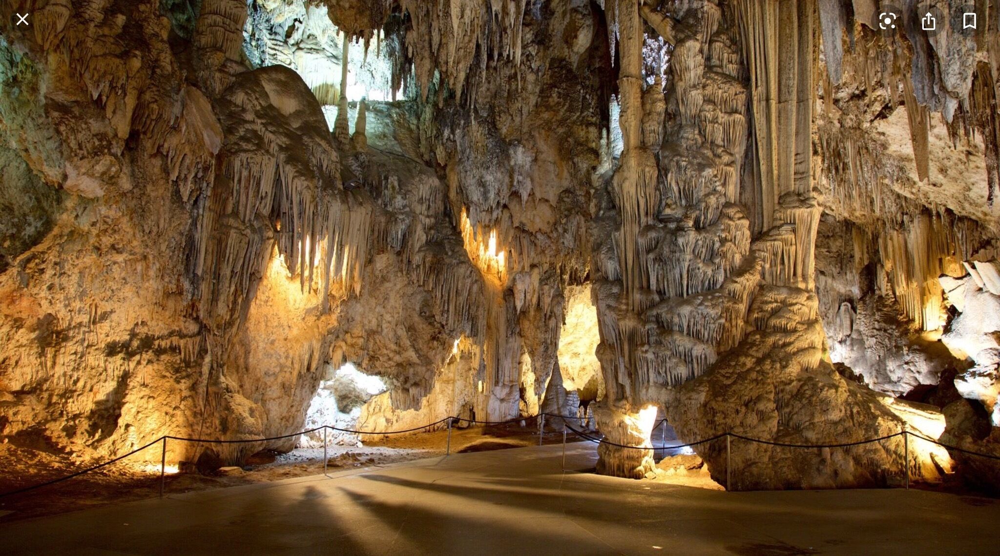 Une grotte ornée de stalactites et de stalagmites, éclairée par un système d’éclairage artificiel.