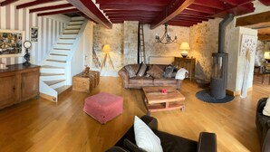 A cozy living room with a staircase, wooden furniture, a fireplace, and a dining area. - Maison de Campagne et Nature (Quincy-sous-le-Mont)