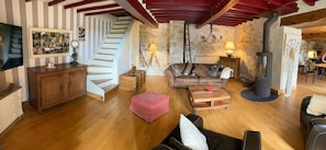 Een knusse woonkamer met een trap, houten meubels, een open haard en een eethoek.