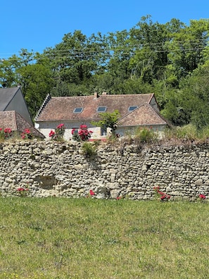 Een stenen muur met een huis op de achtergrond.