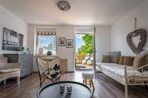 Un salon confortable avec un canapé, un fauteuil, une petite table et une vue sur l’extérieur.