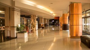 Un vestíbulo amplio con piso pulido, amplias columnas y una zona de recepción.