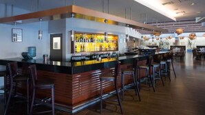 Un moderno espacio de bar con una barra, taburetes y una variedad de botellas.