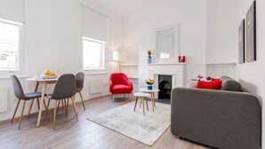 Un salon moderne comprenant un coin repas, un fauteuil rouge, un canapé gris et une cheminée.