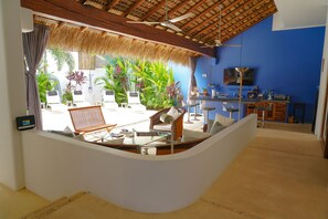 Quarto com balcão branco curvo, ventilador de teto, televisão e parede azul.