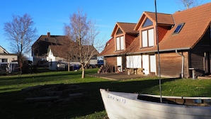 A white boat with "DAV W 13" on its side, a grassy area, and a building with a red-tiled roof. - Wassersportlers Traum (Wiek)
