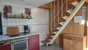 A kitchen with a red oven, a coffee maker, and a wooden staircase. - Wassersportlers Traum (Wiek)