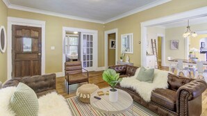 A living room with a brown leather sofa, a round coffee table, and a striped rug. - Stylish Bungalow | Near Cooper-Young, Eats & Beats (Memphis)