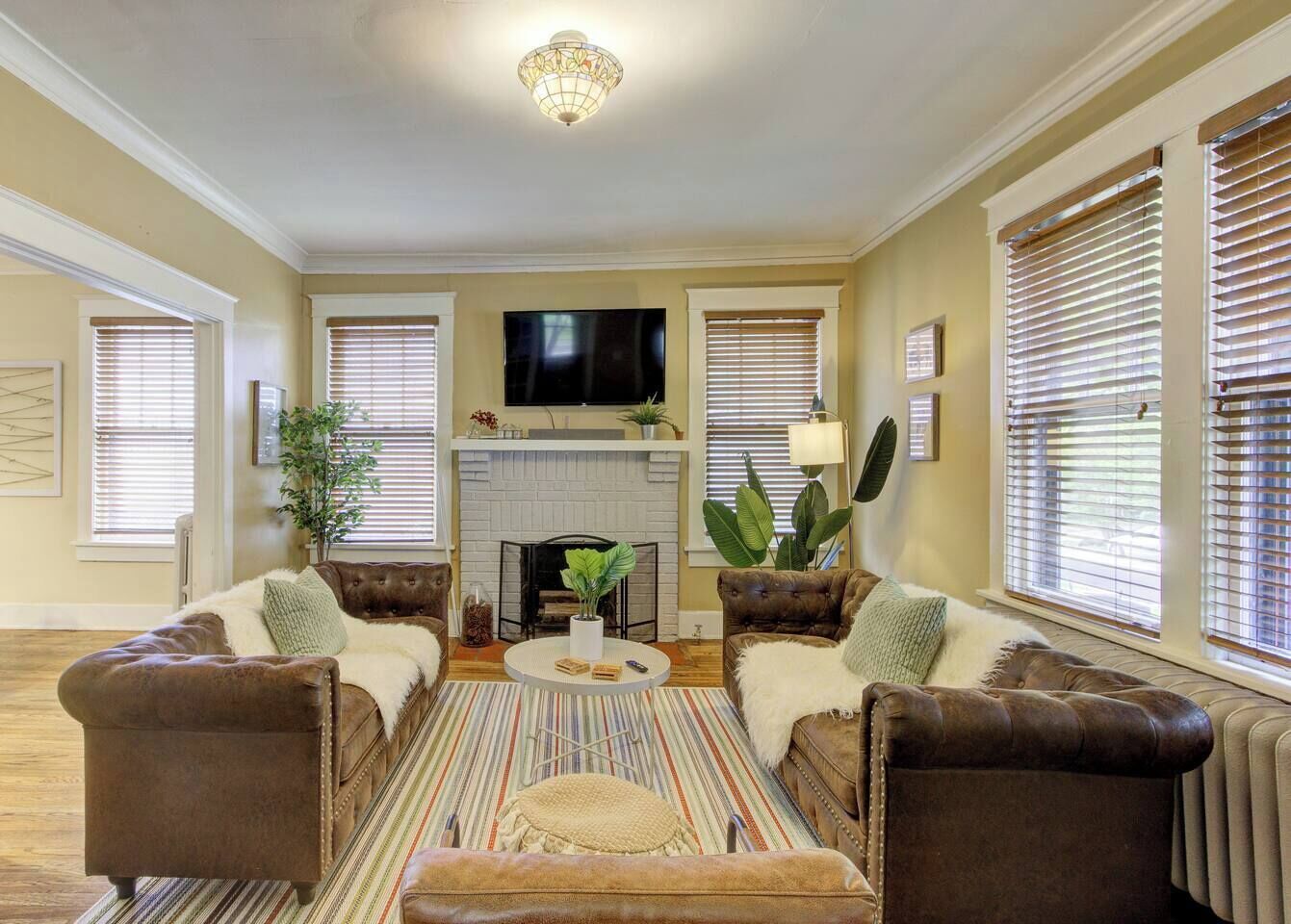 A living room with a fireplace, two leather sofas, a coffee table, and a television.