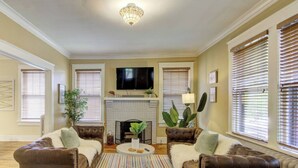 A living room with a fireplace, two leather sofas, a coffee table, and a television. - Stylish Bungalow | Near Cooper-Young, Eats & Beats (Memphis)