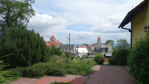 A pathway leading to a building with a red roof, surrounded by greenery and a clear sky.