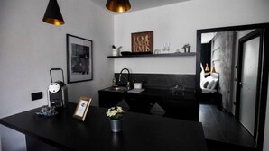 A modern kitchen with a black countertop, a coffee machine, a framed picture, and a small plant.