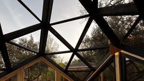 A high-ceilinged room with a bed, wooden beams, and a view of the outdoors. - Le Mas Cabanids (Maureillas-Las-Illas)