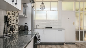 A modern kitchen with white cabinets, a black countertop, and a window with frosted glass.