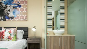 A modern bedroom with a bed, bedside table, lamp, and a large wall painting.
