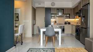 A modern kitchen with a dining area, stainless steel appliances, and a clock on the wall.