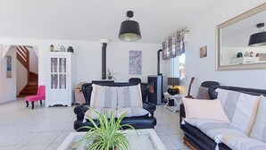 Een woonkamer met een bank, fauteuil, bijzettafeltje en een potplant.