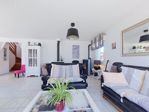 Ein Wohnzimmer mit Sofa, Sesseln, Couchtisch und einem Blumentopf.