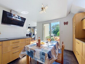 Een moderne keuken met een eettafel gedekt voor twee personen, een televisie boven de aanrecht en uitzicht op de omgeving.