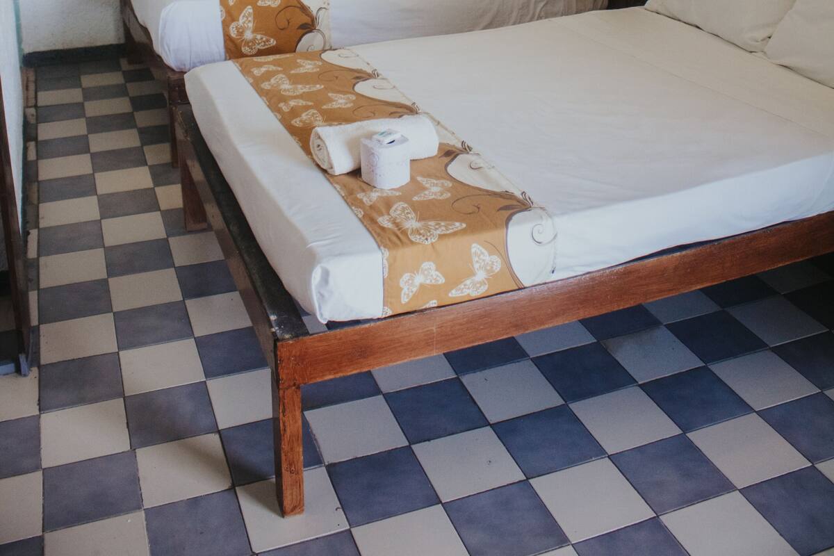 Una habitació amb dos llits, un paviment a escacs i un aire condicionat fixat a la paret.
