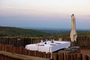 Une table à manger installée à l’extérieur, offrant une vue sur un paysage vallonné.