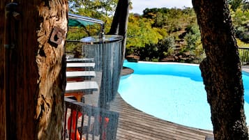 Una piscina al aire libre, sombrillas, sillones reclinables de piscina