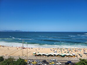 Une plage avec des parasols, une route et des voitures.