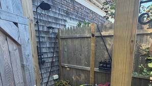 A wooden fence with a gate, a hose, and potted plants. - Modern 1 bed/Studio - Steps from the Center of Town (Provincetown)