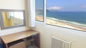 Habitación con escritorio, silla y un amplio ventanal con vista a la playa.