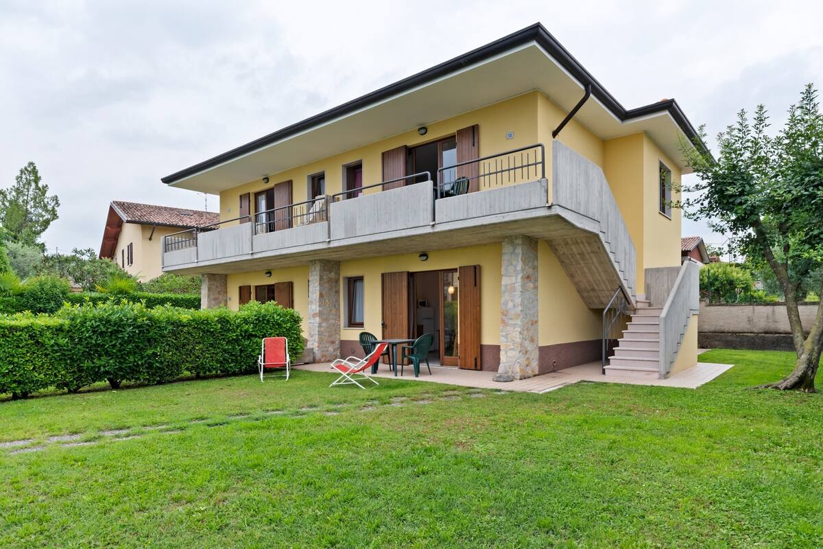 Une maison à deux étages dotée d’un balcon, d’un escalier et d’un petit espace extérieur aménagé pour s’asseoir.
