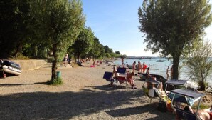 Ein Strand mit badenden Personen, Booten und Sonnenschirmen.