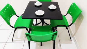 Een kleine eettafel met vier stoelen, elk met een groene zitting en rugleuning.