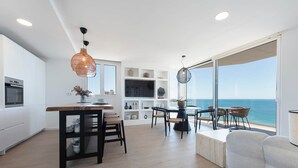 A modern kitchen with a dining area, large windows, and a view of the ocean. - Modern stunning views sea front SEA WATER APARTMENT (Alicante)
