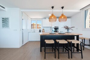 Et moderne køkken med en central ø, sorte barstole og udsigt over byen.