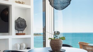 A round table with a woven pot and a chair, a shelf with decorative items, and a view of the sea. - Modern stunning views sea front SEA WATER APARTMENT (Alicante)