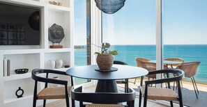 Un salon moderne avec une table ronde, des fauteuils en osier et une vue sur la mer.