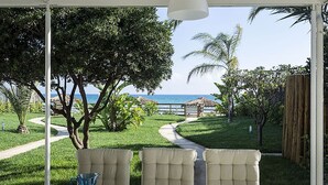 Eine Terrasse mit Esstisch, mit Blick auf eine Rasenfläche und einen Weg zum Meer.