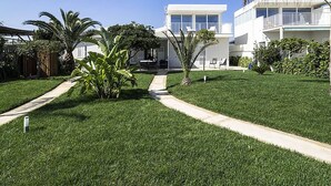 Ein modernes, zweistöckiges Haus mit gepflegtem Rasen, einem Weg, der zum Eingang führt, und einer kleinen Terrasse.