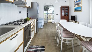 Eine moderne Küche mit weißen Schränken, einem Gasherd und einem Essbereich mit weißem Tisch und Stühlen.