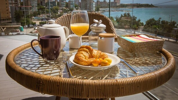 Desayuno en un balcón con croissants, zumo de naranja y café.