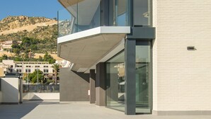 Un edificio moderno con piscina, grandes ventanales y vistas a un paisaje montañoso.