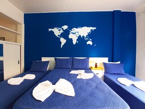 A hotel room with two beds, a world map on the wall, and a small table with a lamp. - TC1209 Apto Beira-Mar Copa 3 (Rio de Janeiro)