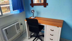 Un espacio de oficina compacto con un escritorio de madera, una silla de oficina negra y un archivador blanco.